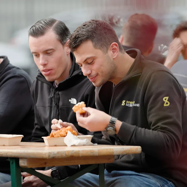 Twee mannen die kibbeling aan het eten zijn.
