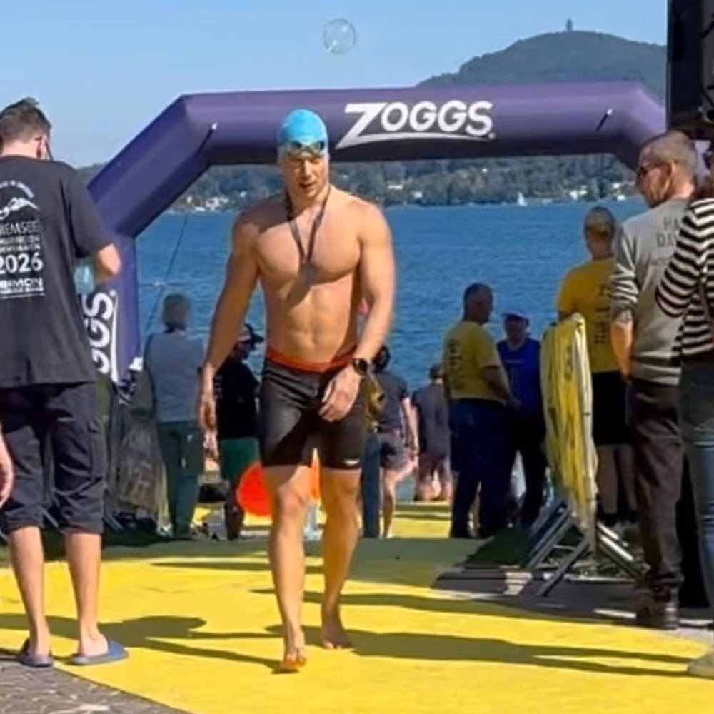 Ein Schwimmer läuft durch das Ziel eines Schwimmwettkampfs.