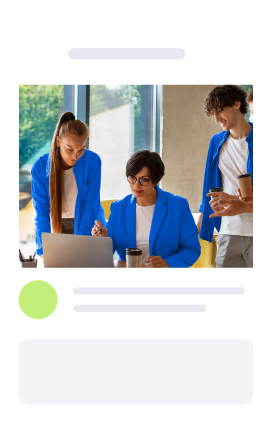 Three people in blue jackets collaborating around a laptop in a bright office.