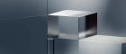 A transparent glass cube sitting on a light surface against a dark background.