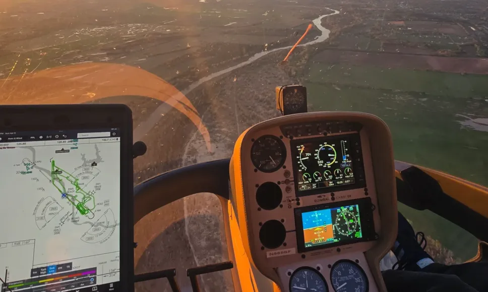 Cockpit view of an aircraft flying over farmland with flight instruments and navigation map visible.