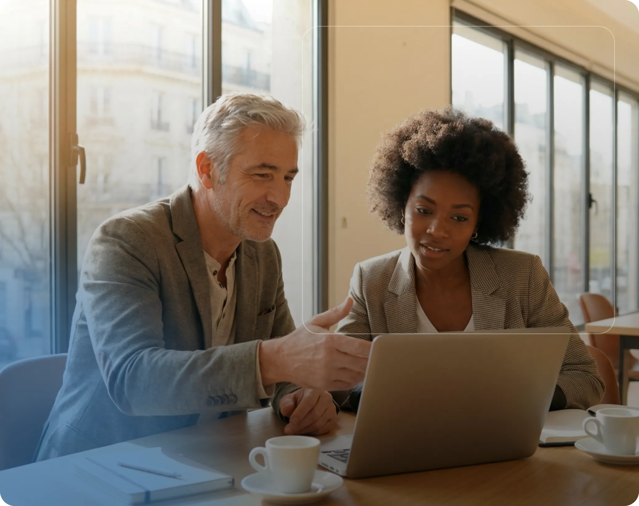 Un homme et une femme discutent devant un ordinateur portable dans un bureau lumineux.