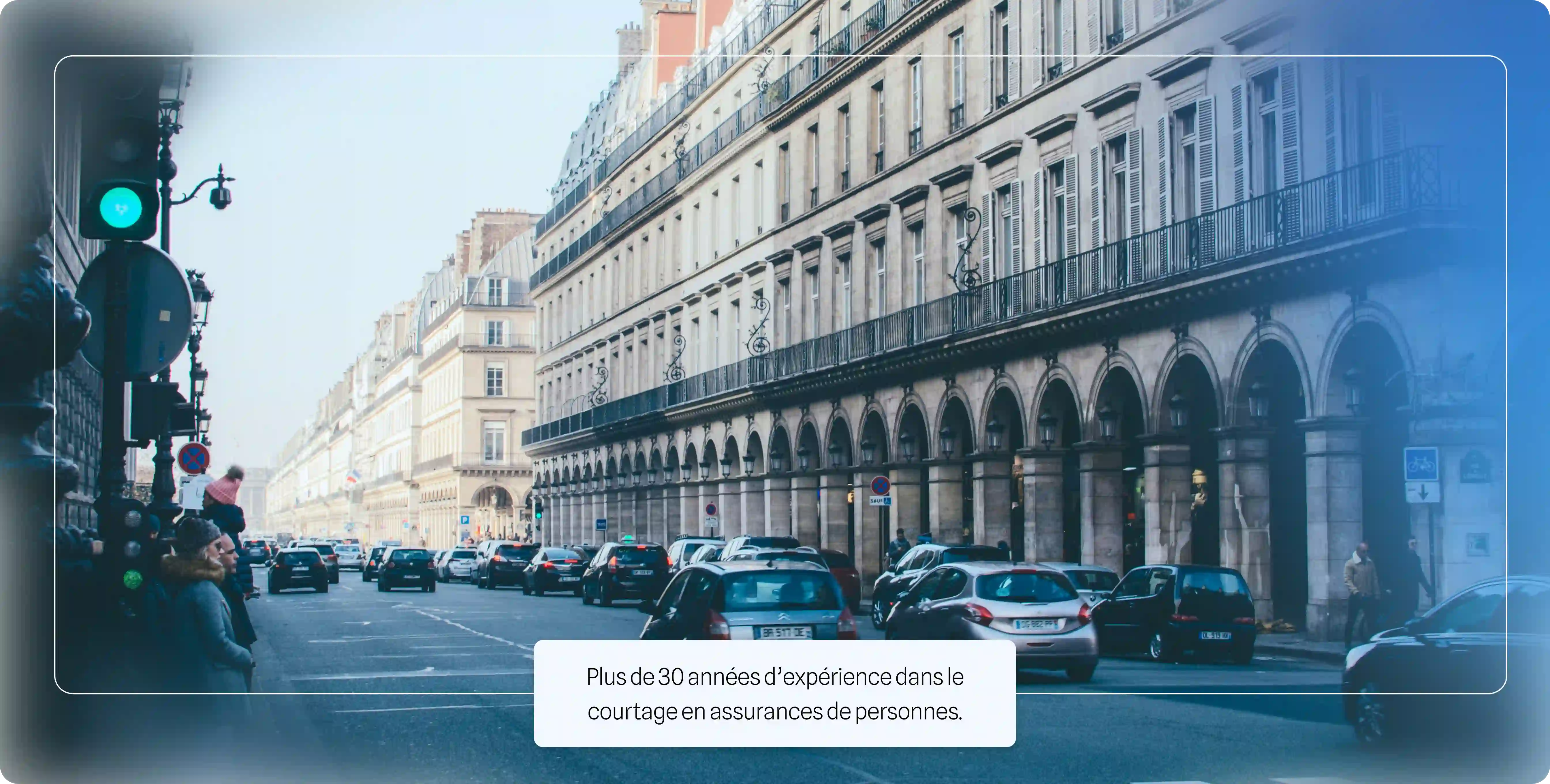 Rue parisienne avec immeubles haussmanniens, voitures en circulation et piétons au feu vert