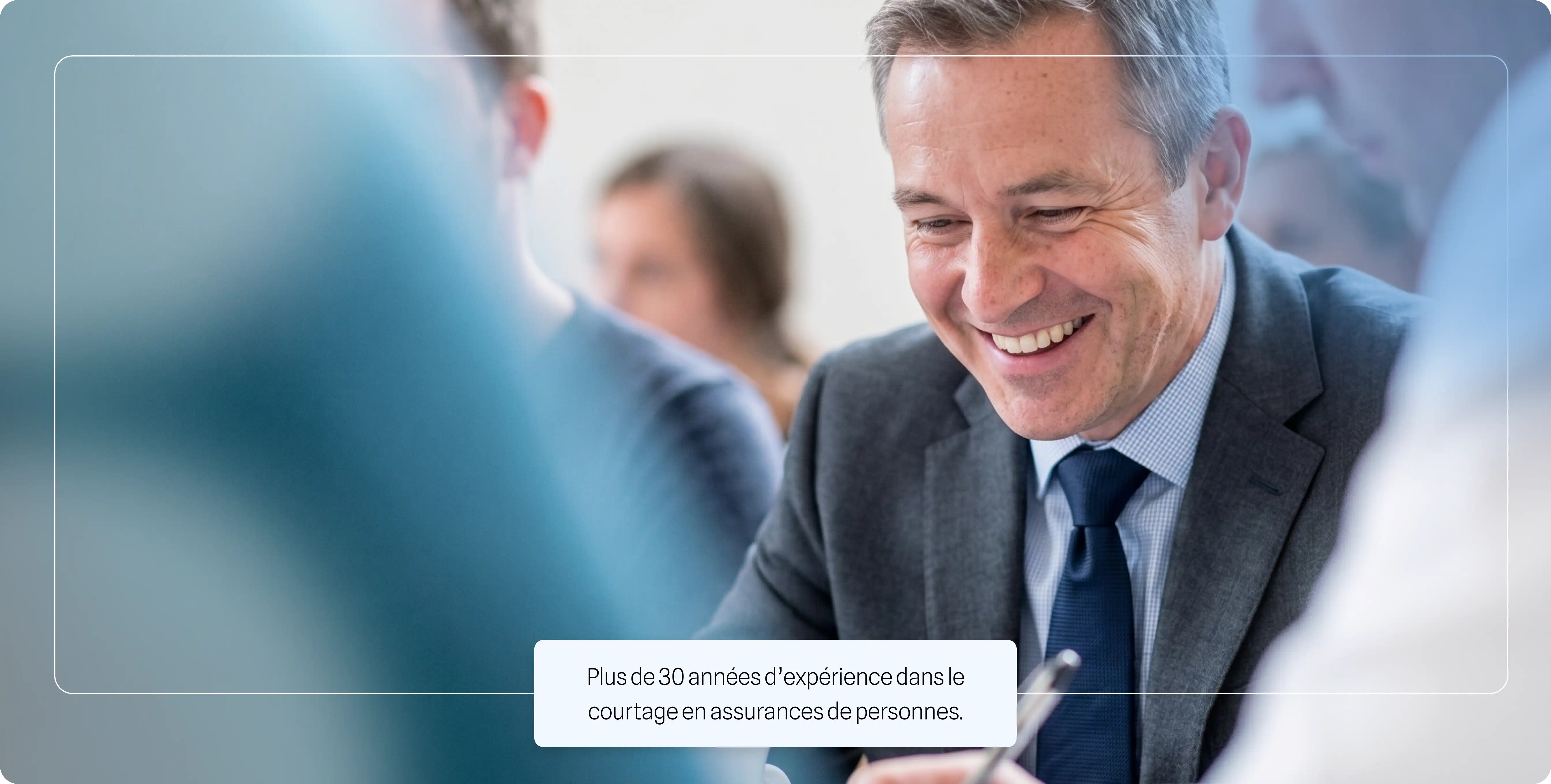 Homme d'affaires souriant portant un costume et une cravate lors d'une réunion.