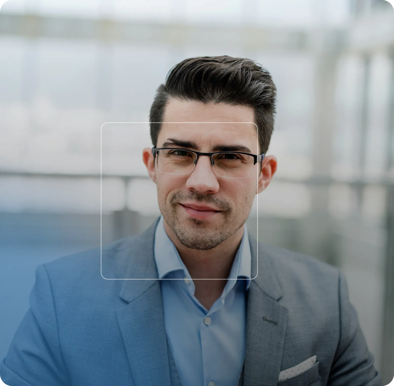 Homme d'affaires souriant portant un costume bleu et des lunettes, en arrière-plan flou.