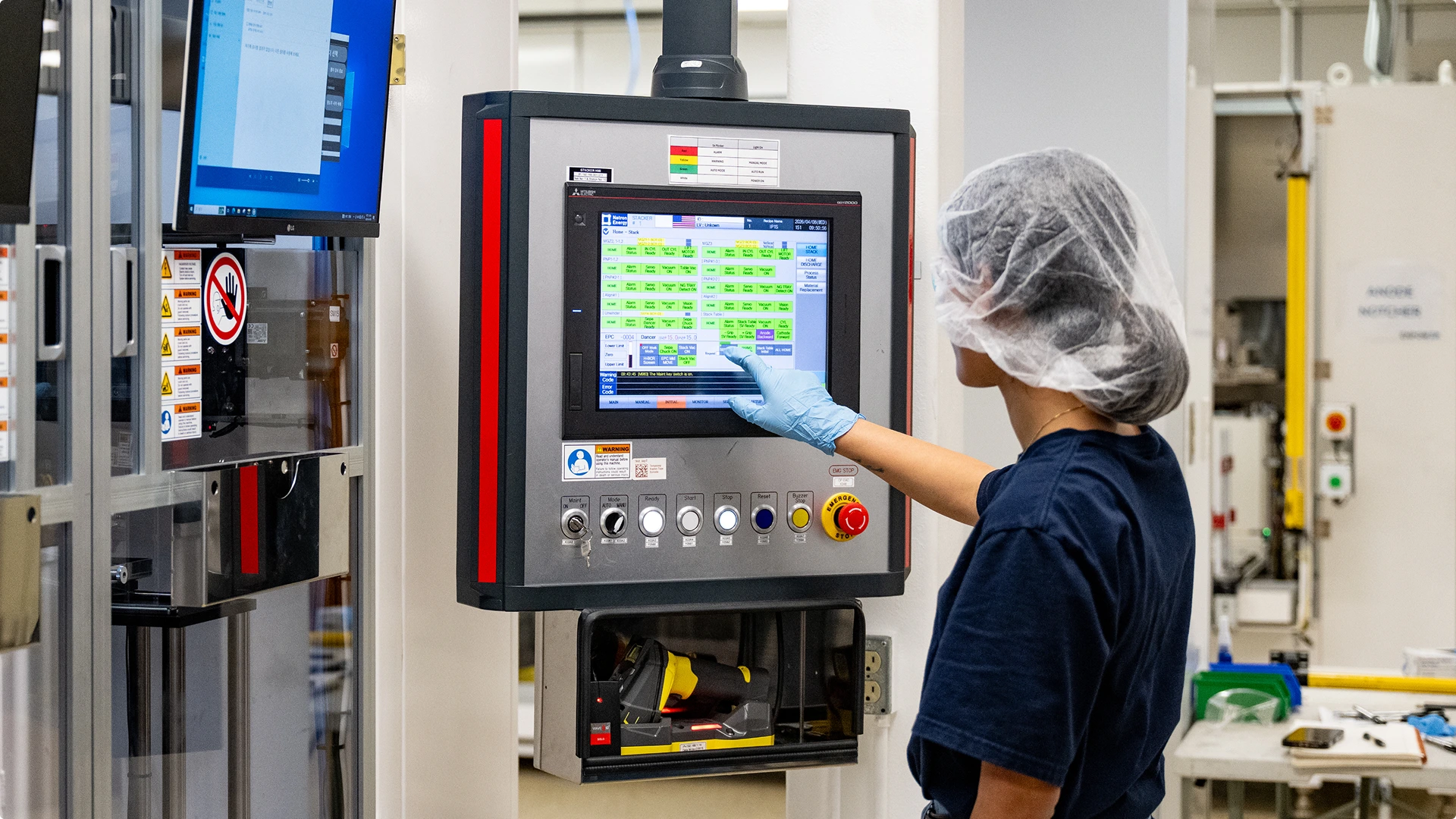 A woman in protective gear using a screen interface in an laboratory enviroment