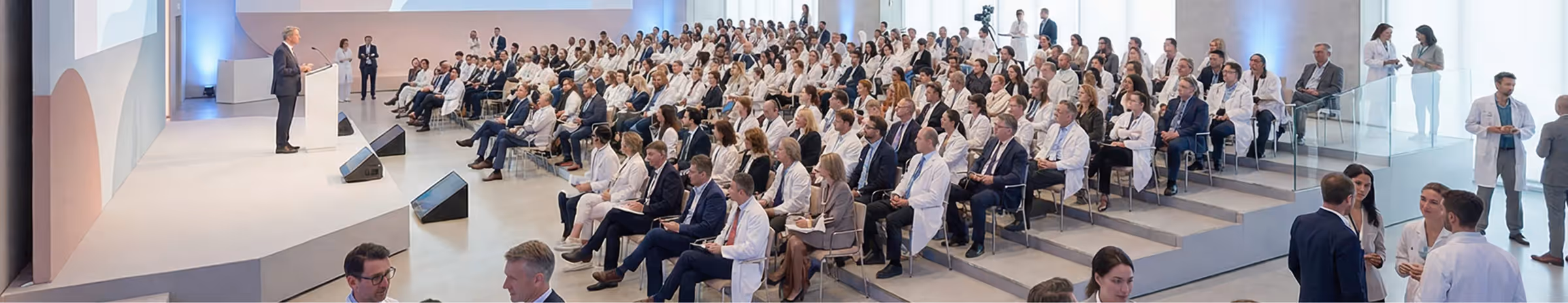 Geschäftsmann hält Vortrag vor großem Publikum aus Ärzten und Fachleuten in einem Konferenzsaal.