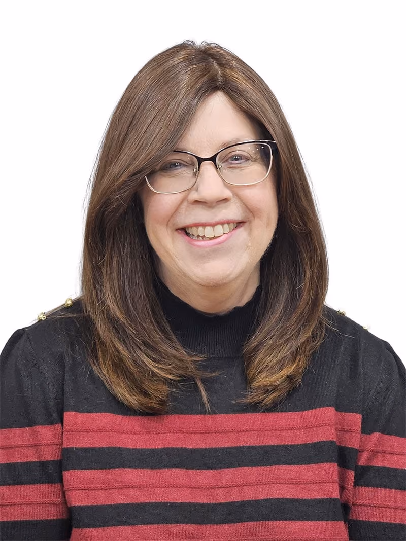 Smiling woman with brown hair and glasses wearing a black and red striped sweater.