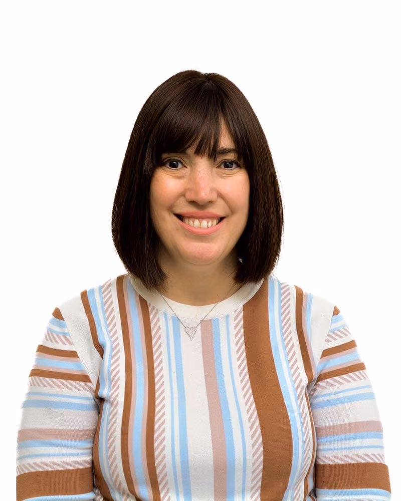Smiling woman with straight dark hair wearing a striped sweater of brown, blue, and white colors.