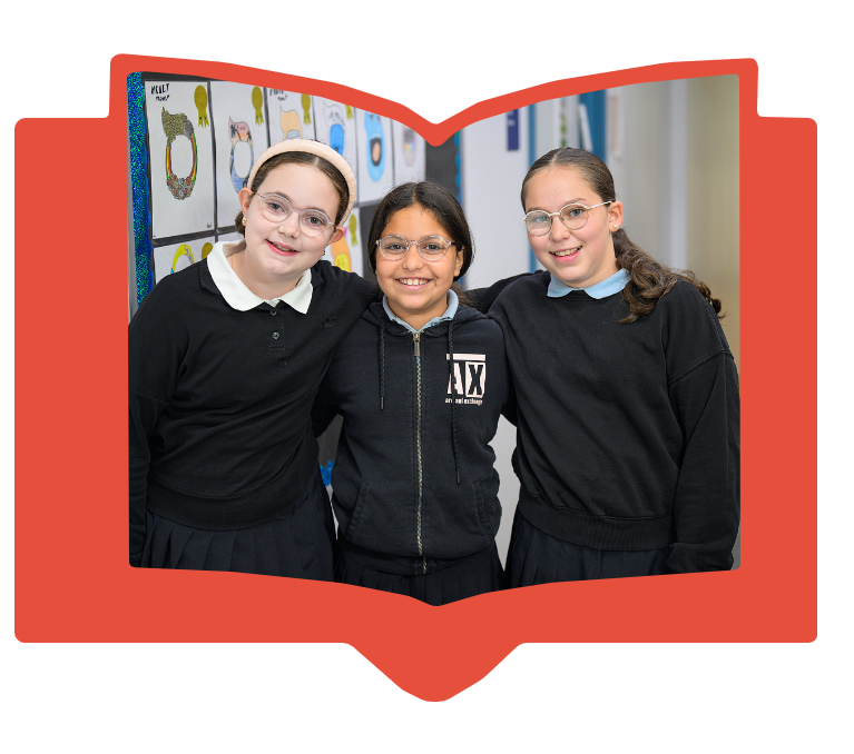 Three smiling girls with glasses in school uniforms standing indoors with arms around each other.