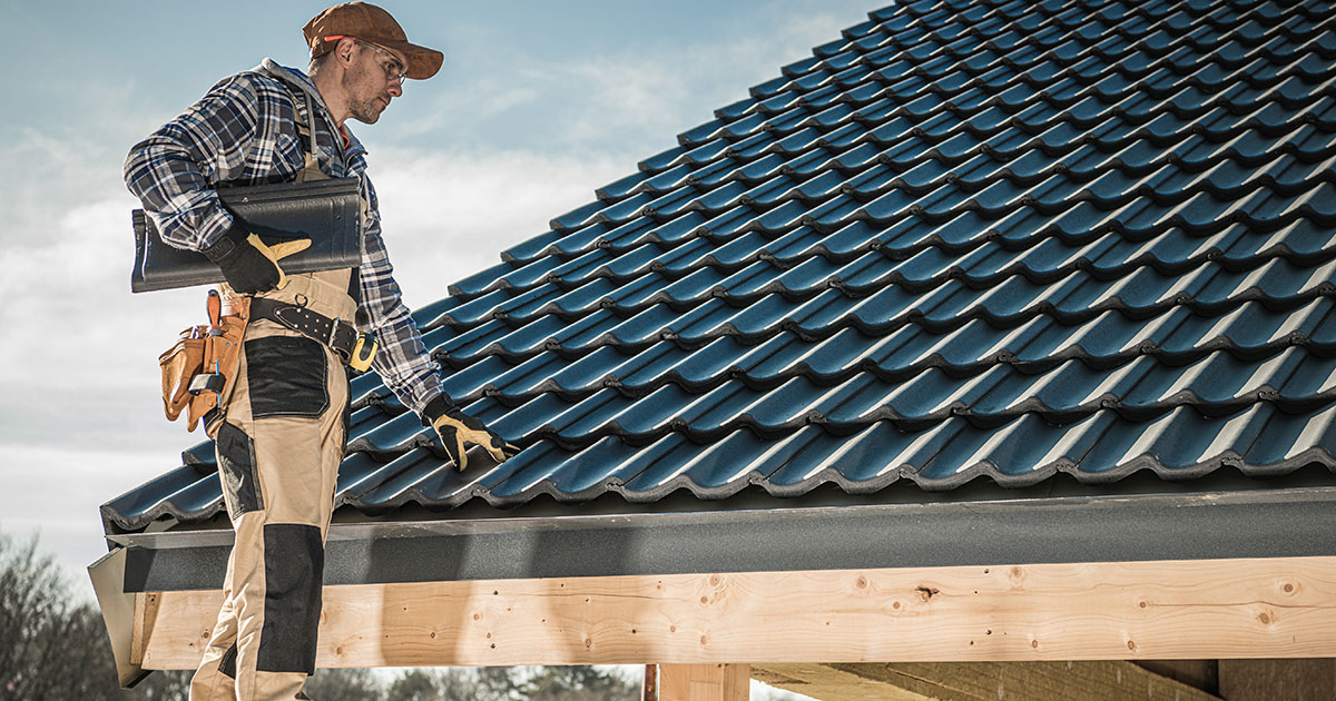 Roofing contractor installing asphalt shingles on a residential roof under a bright blue sky in Palm Harbor, Florida