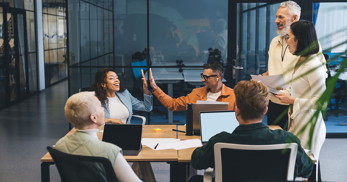 Marketing team collaborating around laptops in an open office