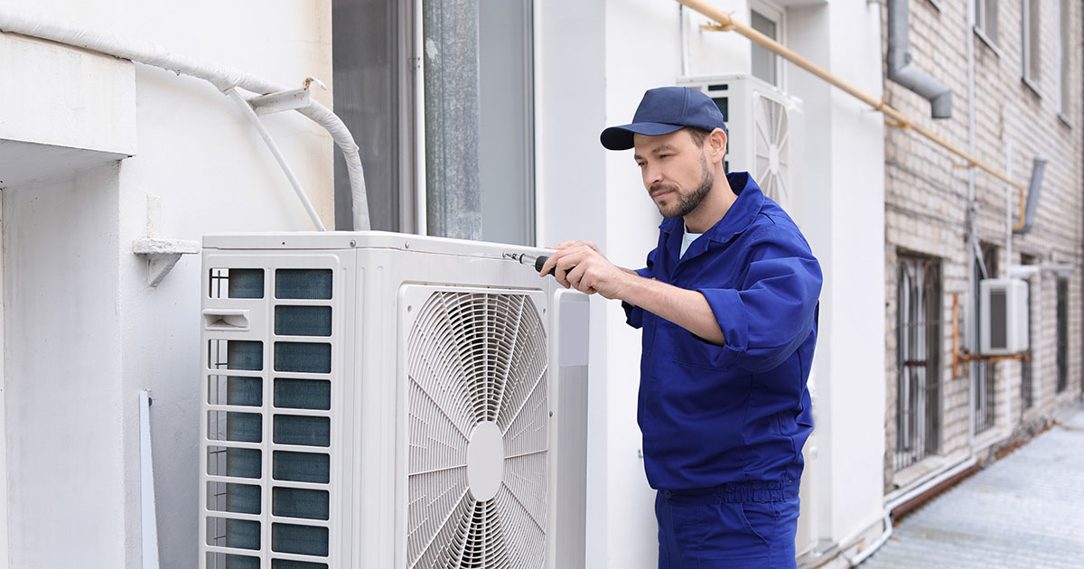 HVAC technician servicing an outdoor air conditioning unit