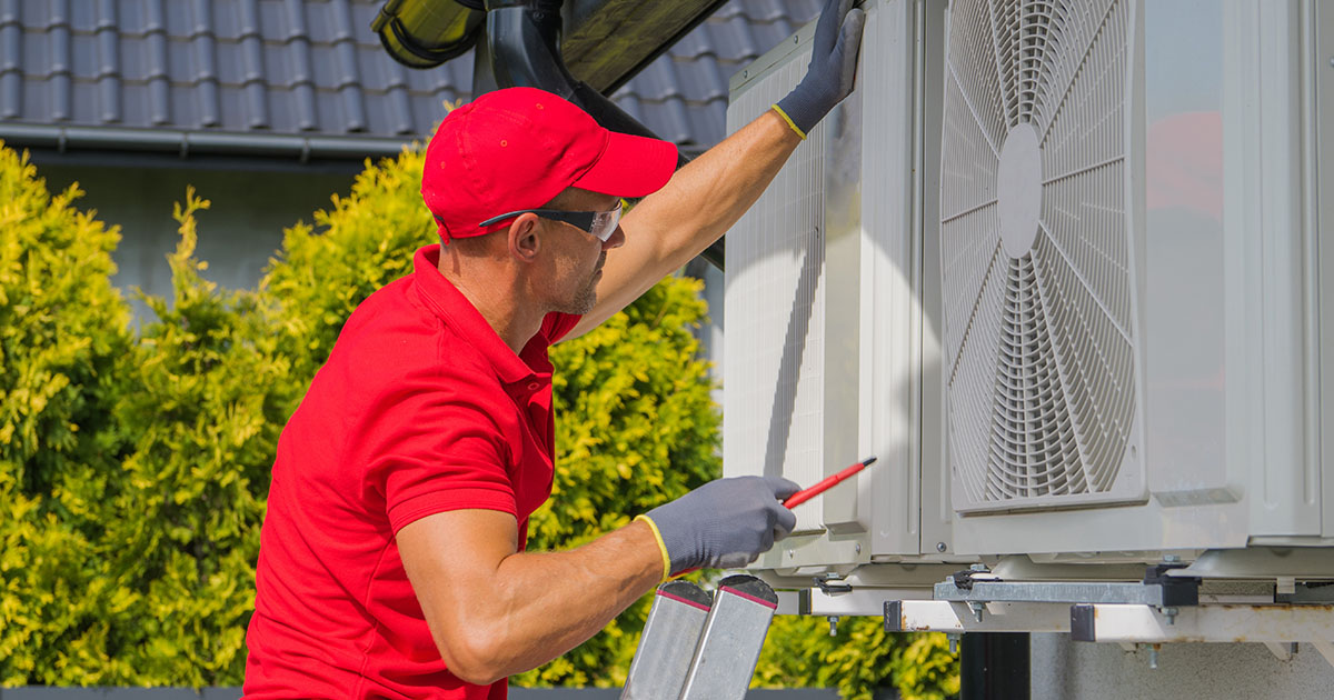 HVAC technician in a red uniform servicing an outdoor air conditioning unit at a South Tampa home