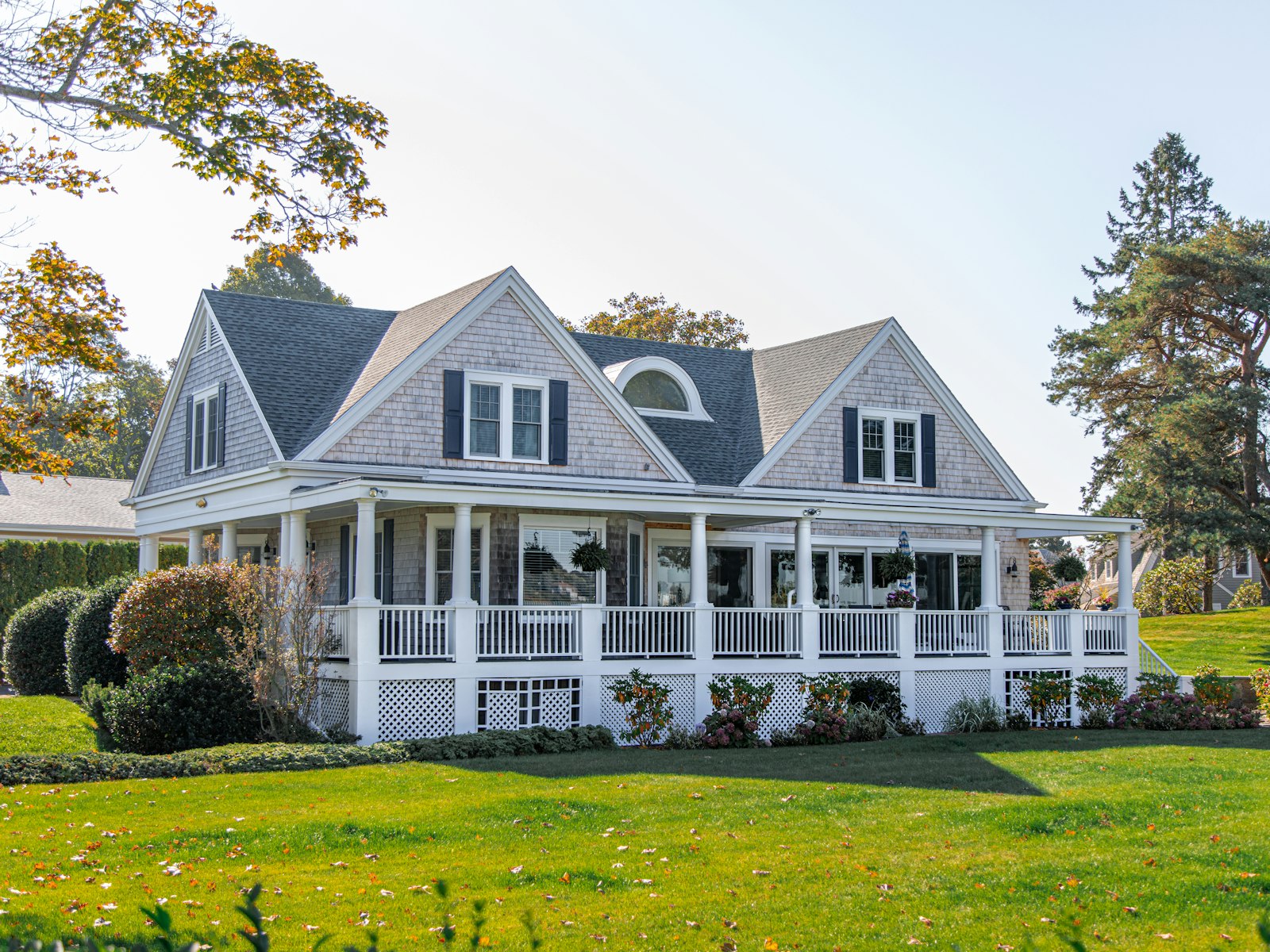 Gray two-story house with a wraparound porch and green lawn