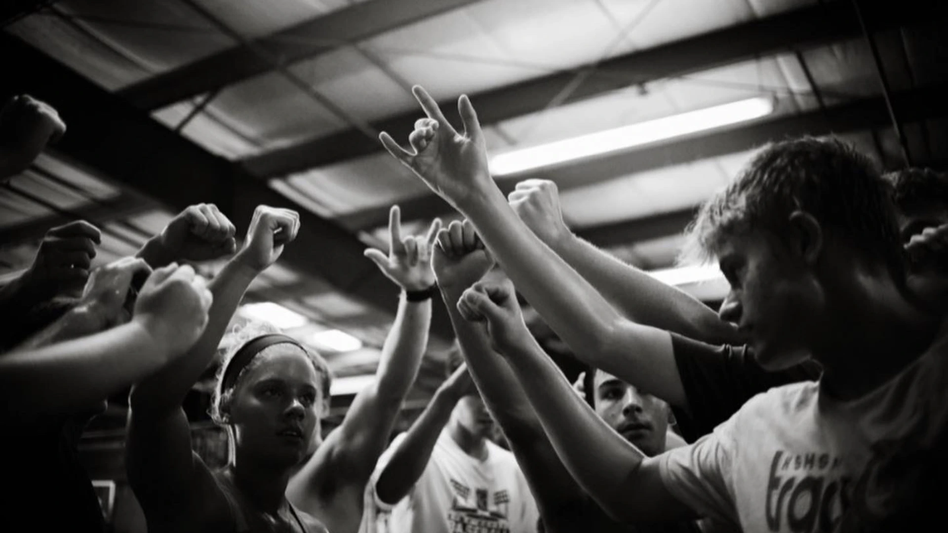 Black and white photo of PSP3 athletes raising their fists together in a team huddle