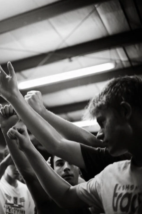 Black and white photo of PSP3 athletes raising their fists together in a team huddle