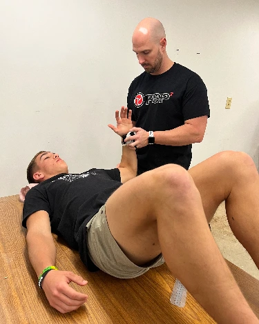 PSP3 coach performing a hands-on movement assessment with an athlete