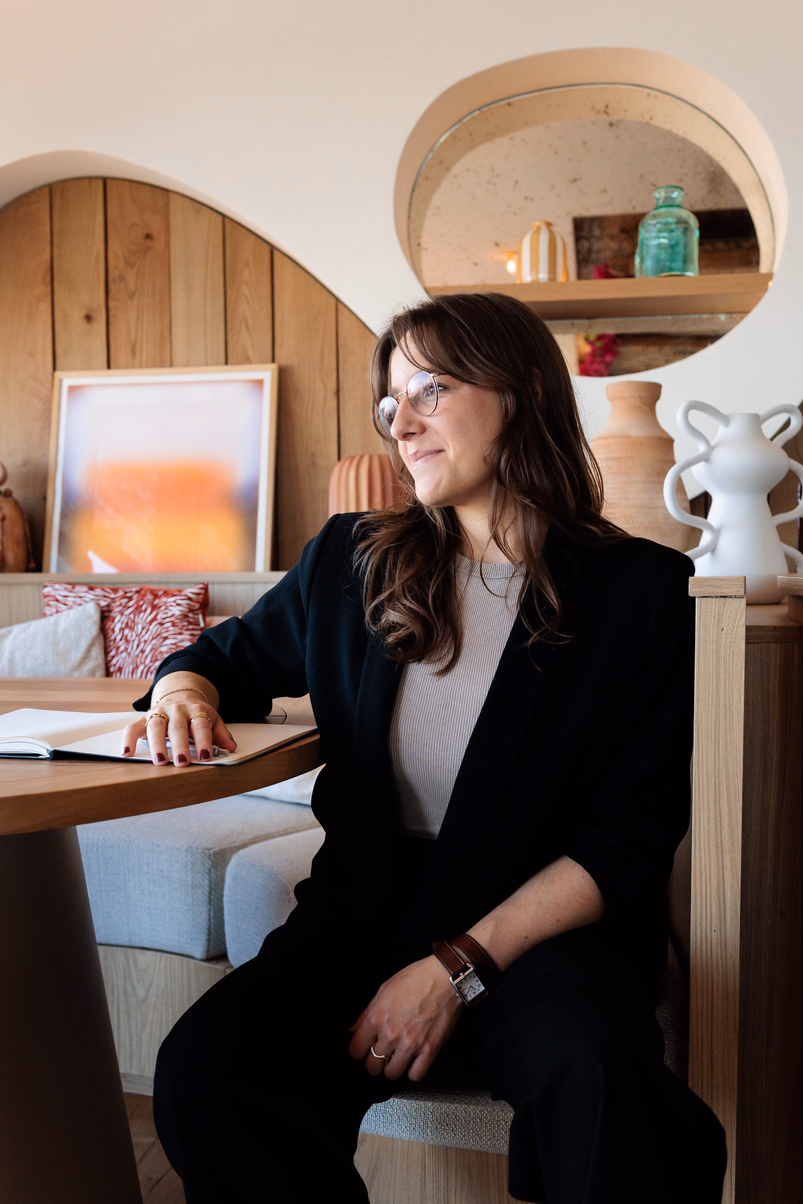 Pauline Réant assise à un bureau en bois, souriante, dans un intérieur chaleureux et élégant