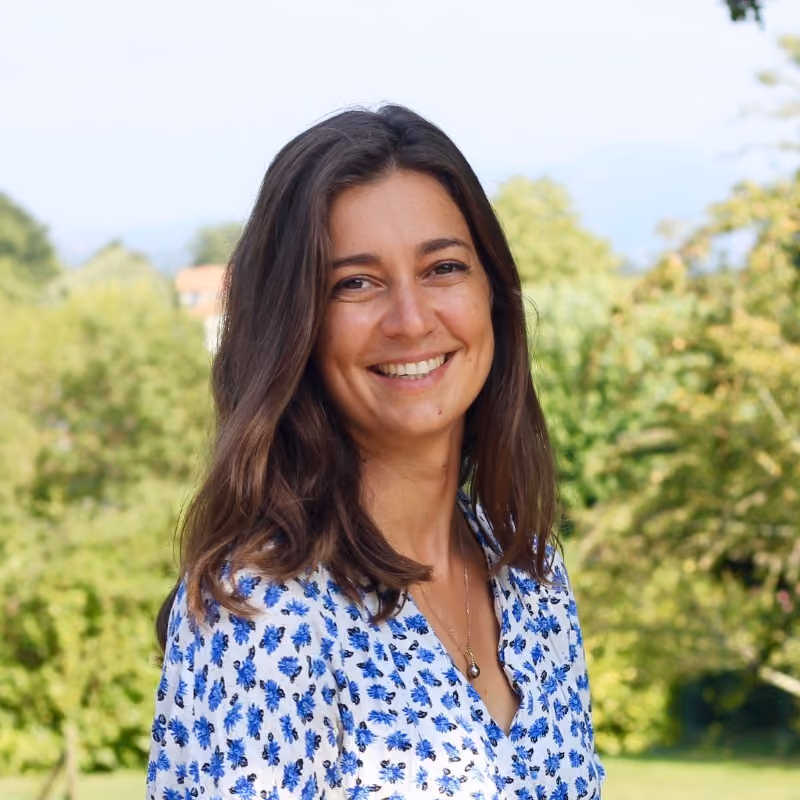 Portrait d'un jeune femme brune souriante devant un jardin