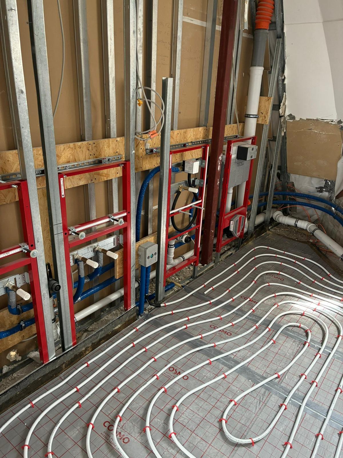 Rohrleitungen und weiße Fußbodenheizungsrohre, die in einem im Bau befindlichen Gebäude verlegt wurden.