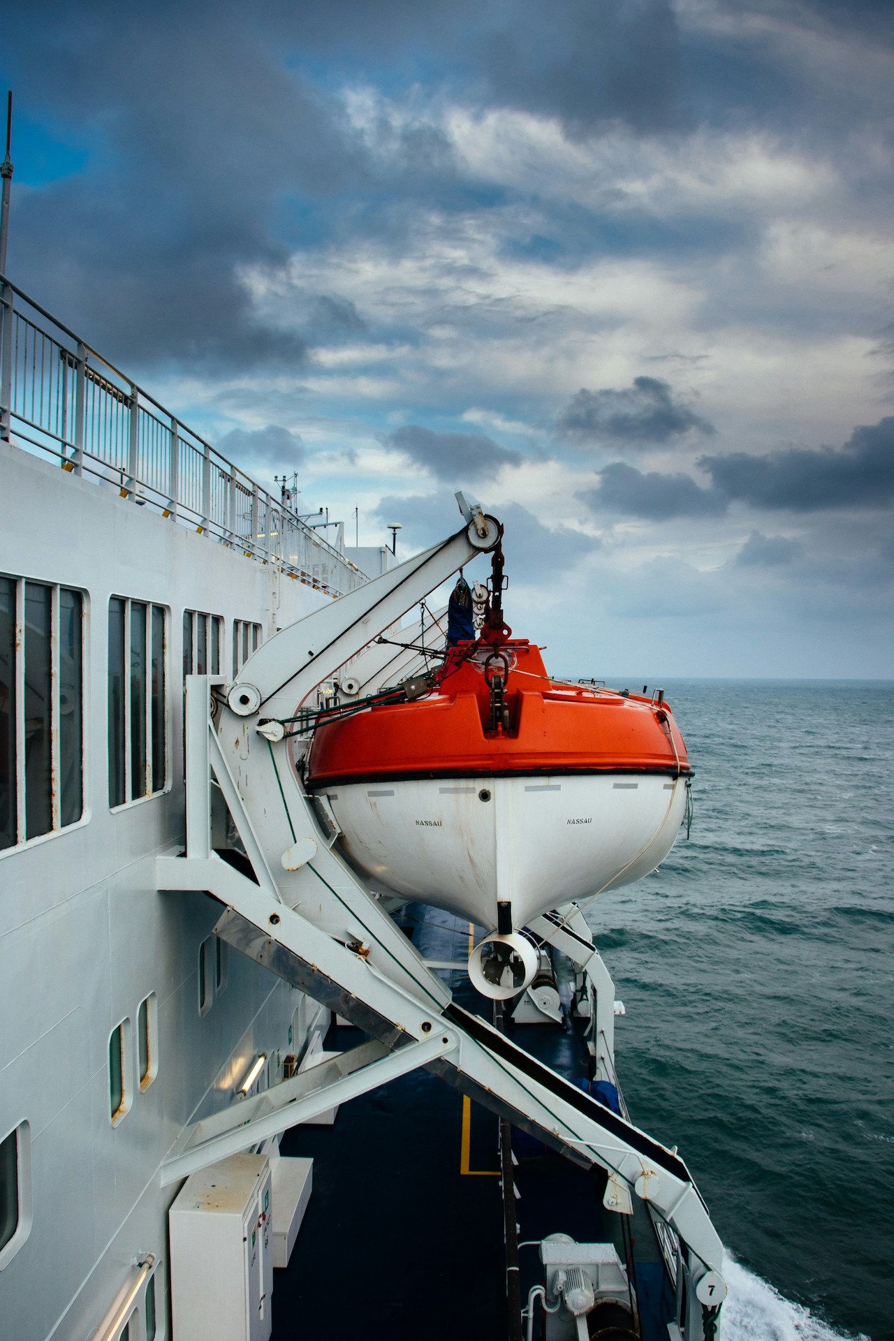 Orange lifeboat in its davit on the side of a passenger ship