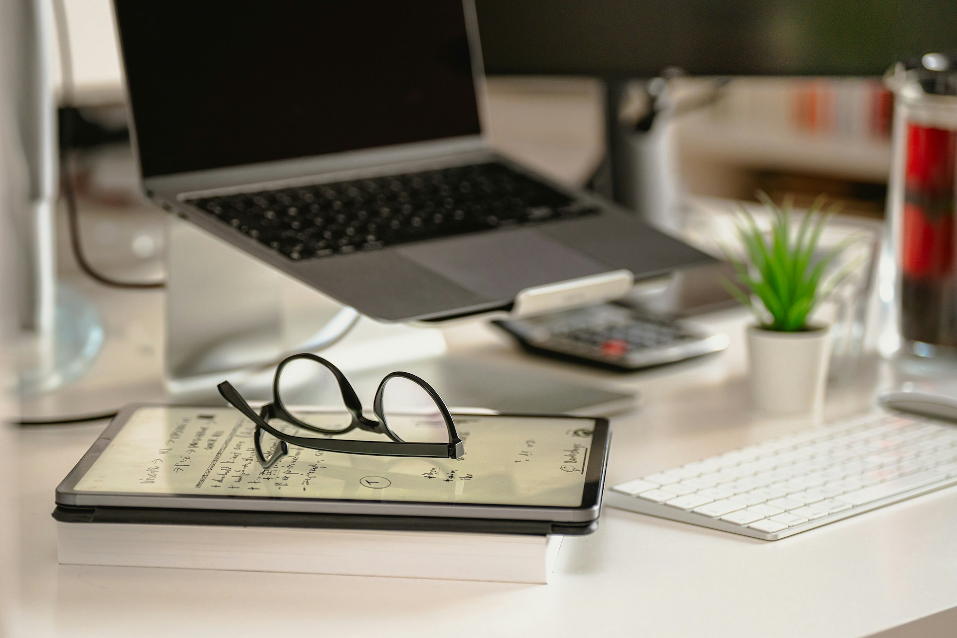 Laptop, reading glasses and notebook on a desk