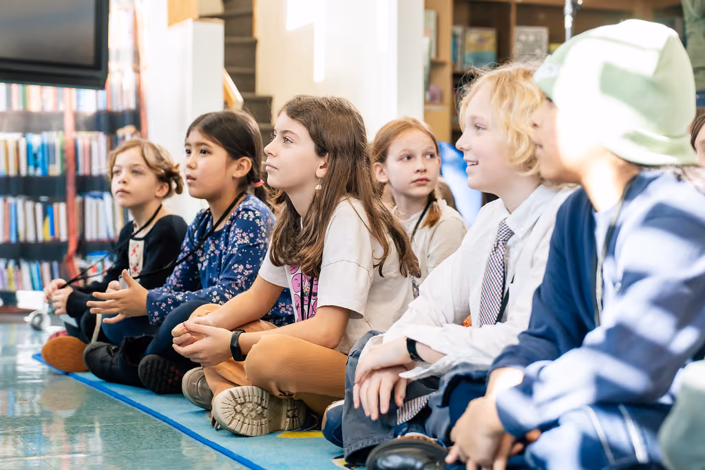 Students sitting on library floor listening attentively during read aloud