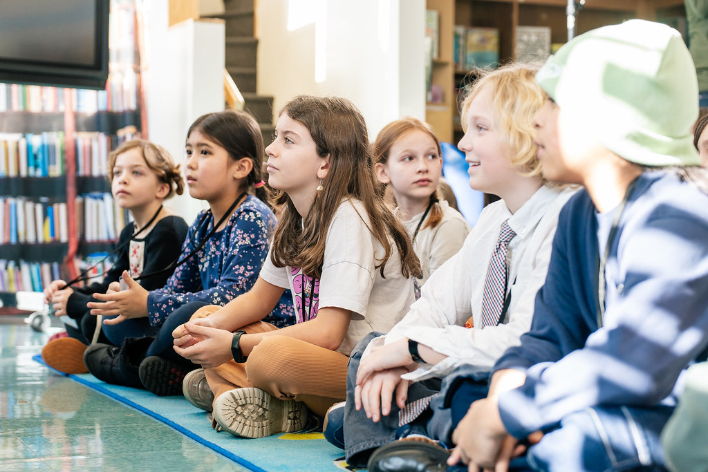 Students sitting on library floor listening attentively during read aloud