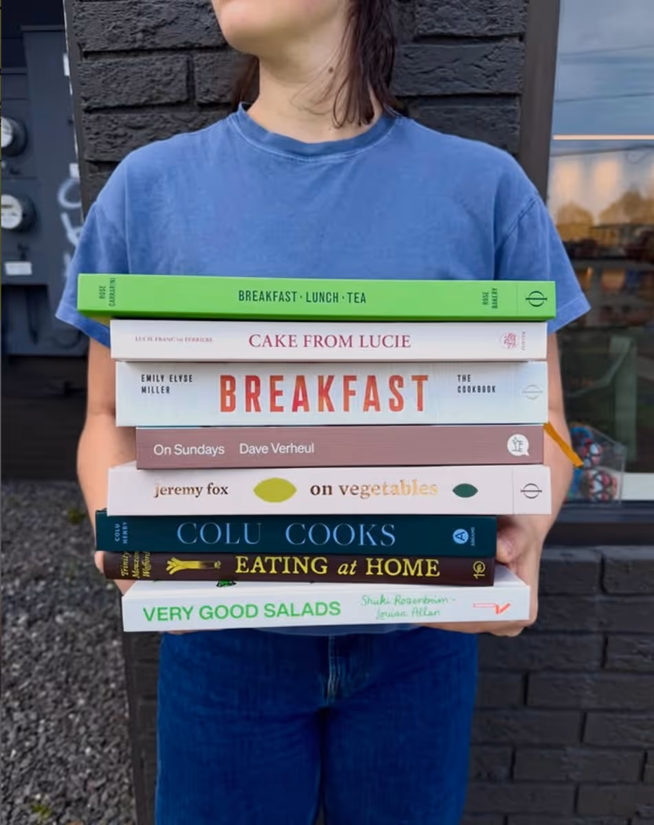 Person holding a stack of cookbooks