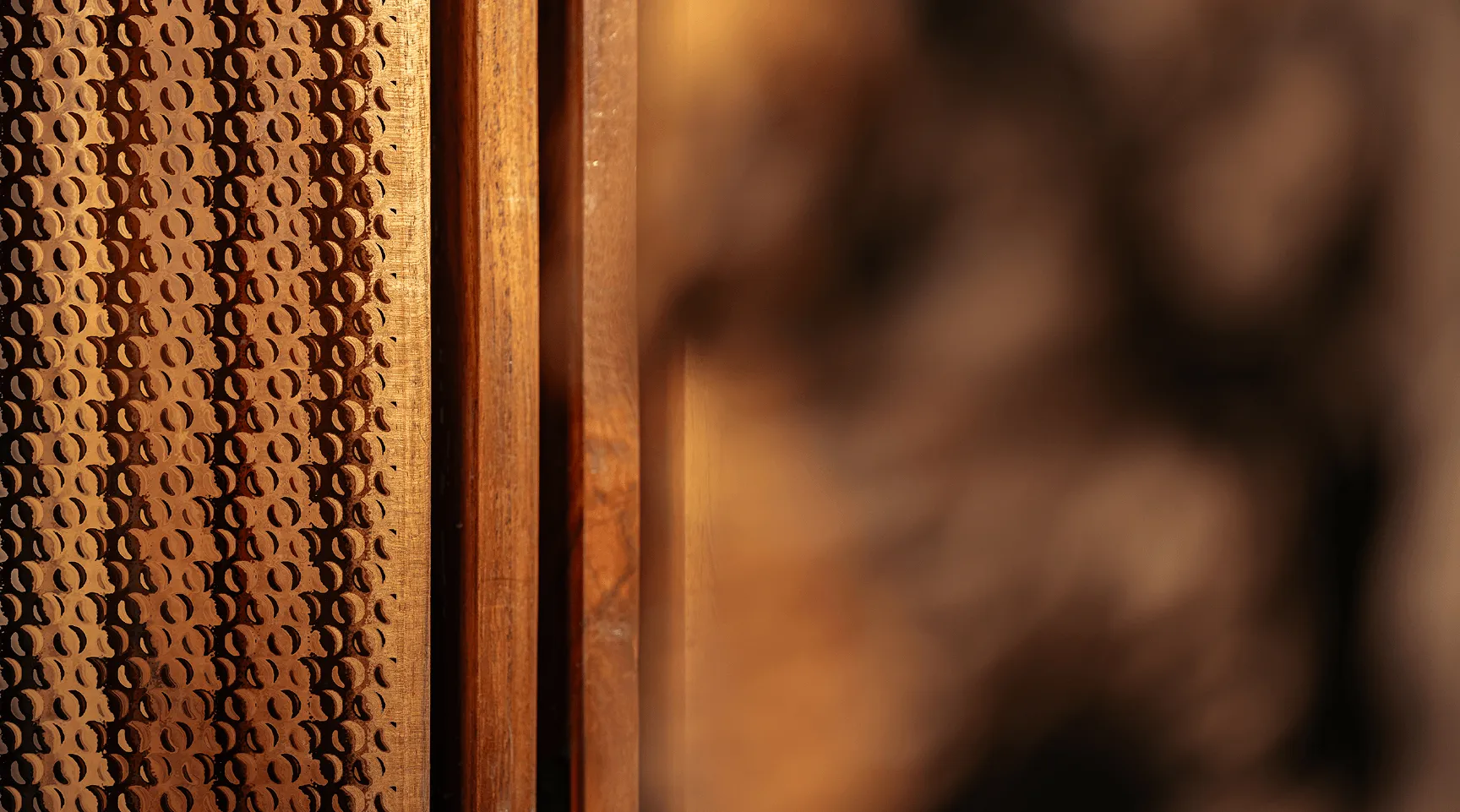 Close-up of wooden surface with circular perforation patterns and warm lighting.