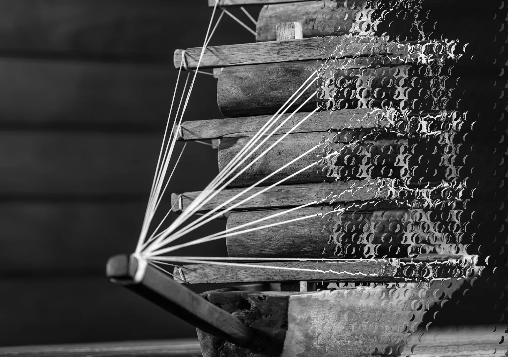 Close-up of an acoustic kalimba with wooden tines and strings, black and white photo.