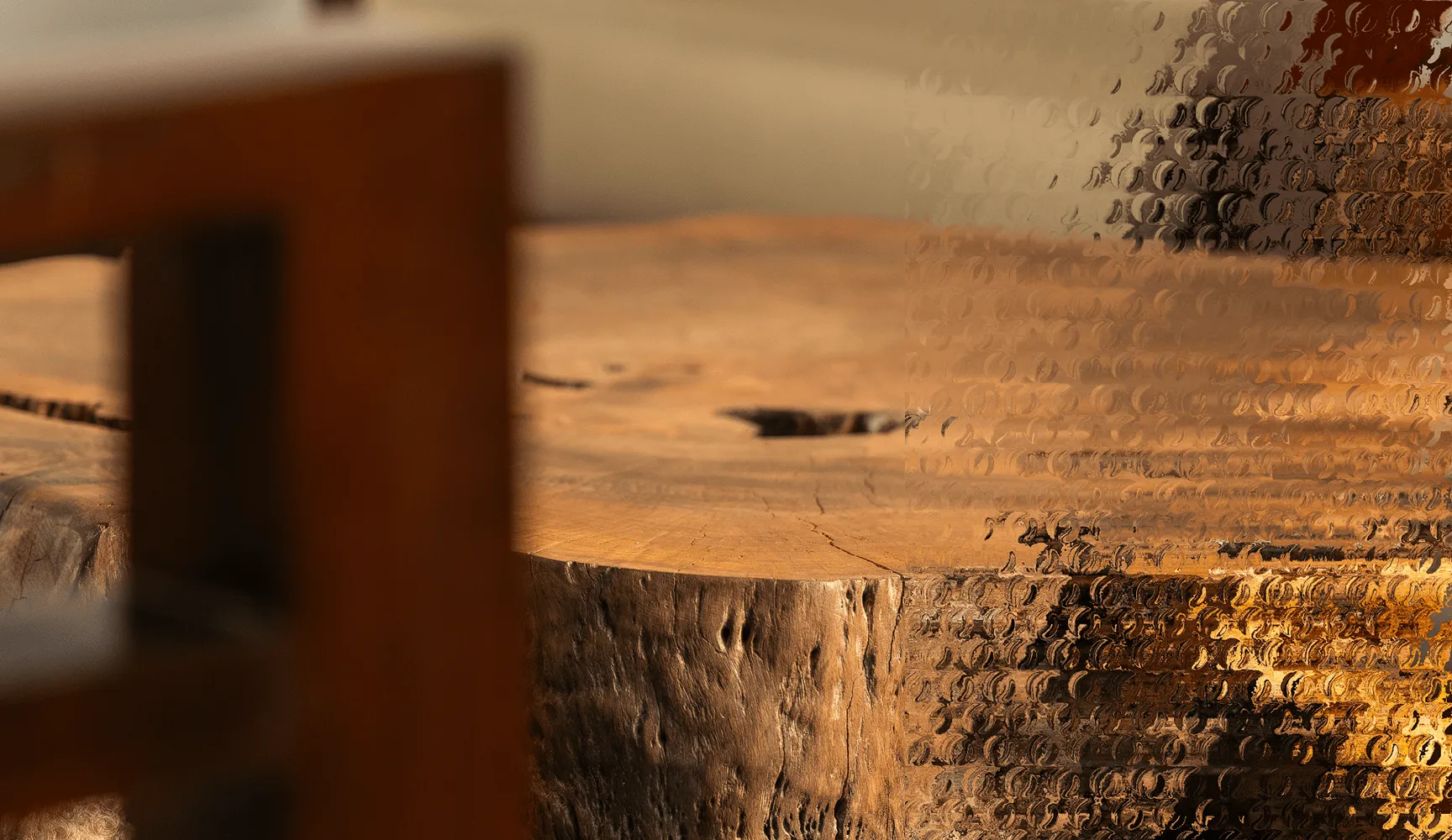 Close-up of a wooden table edge with a glass panel featuring a bubble texture on the right.