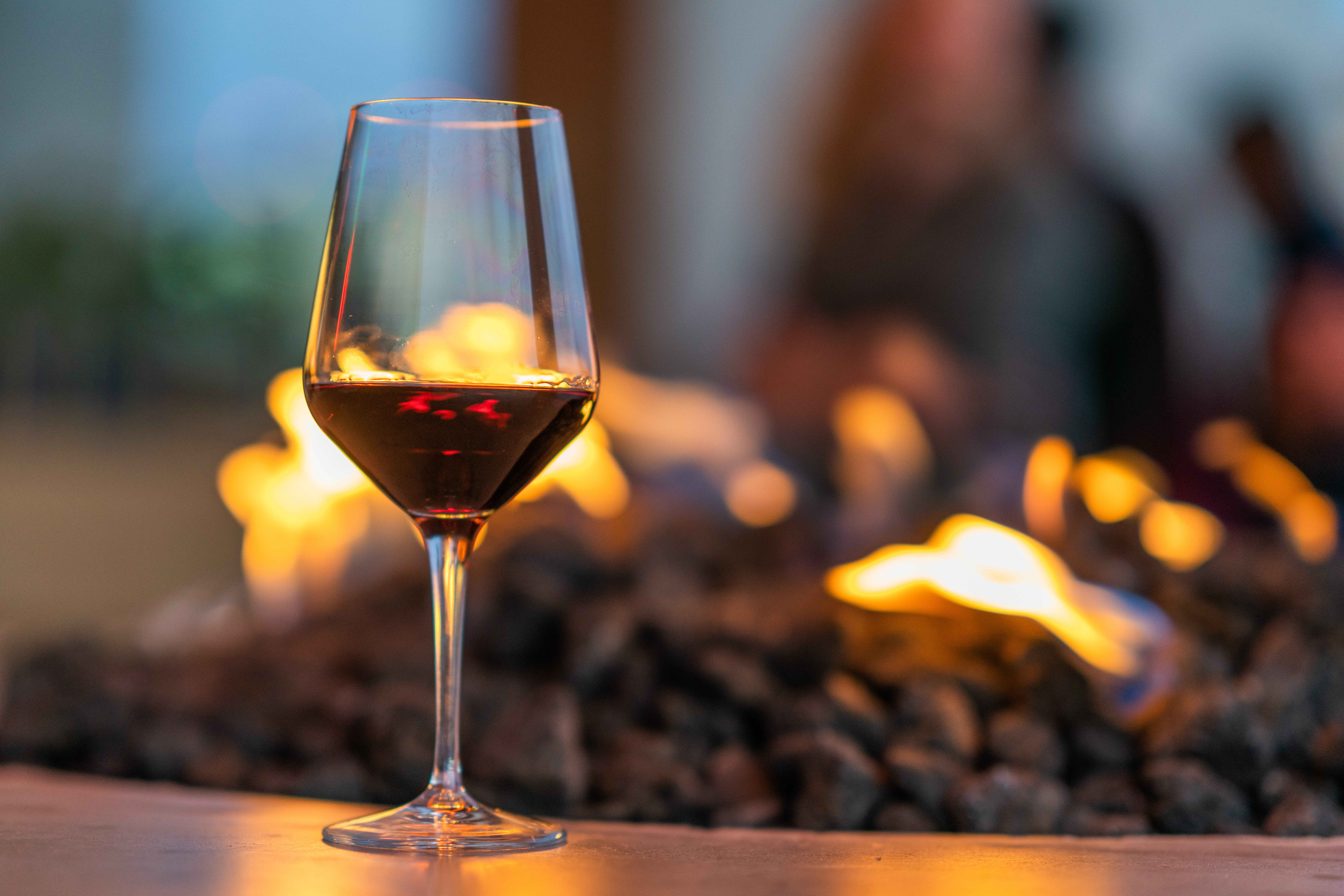 Glass of wine by fire pit stock image