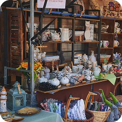 Outdoor market stall with floral arrangements and decorative plants under a yellow canopy.
