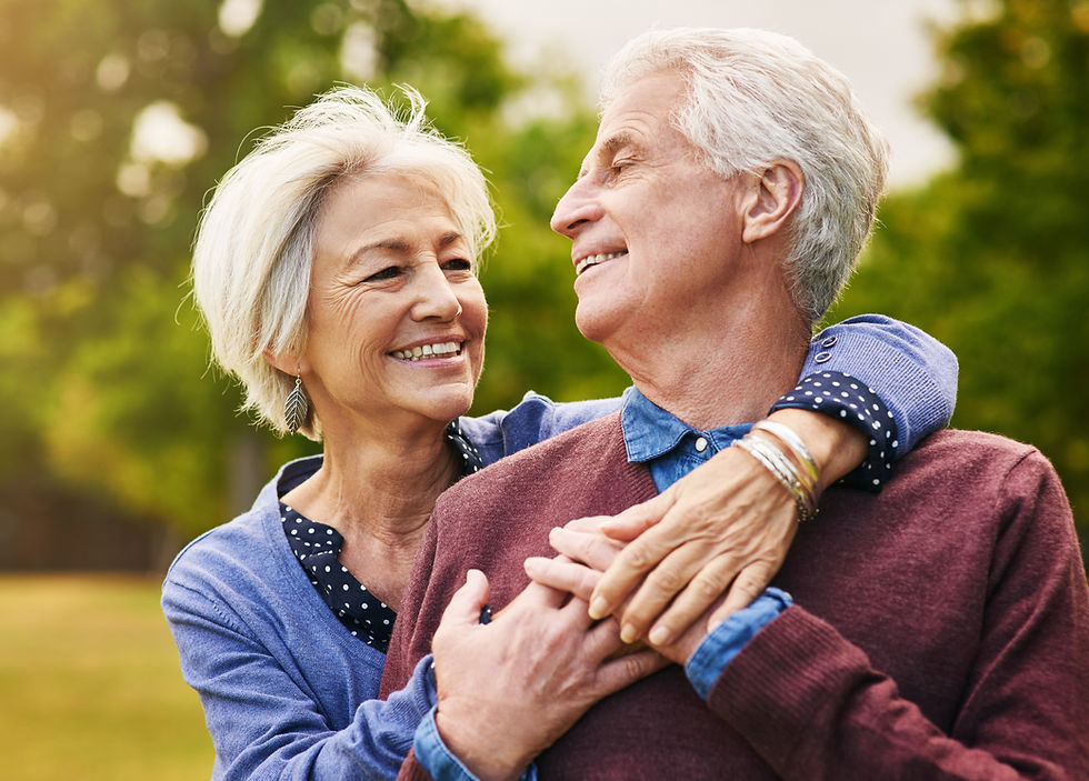 Elderly couple smiling and embracing in a park demonstrate the joy of kindness and love, which is what our dental office wants to spread to our community