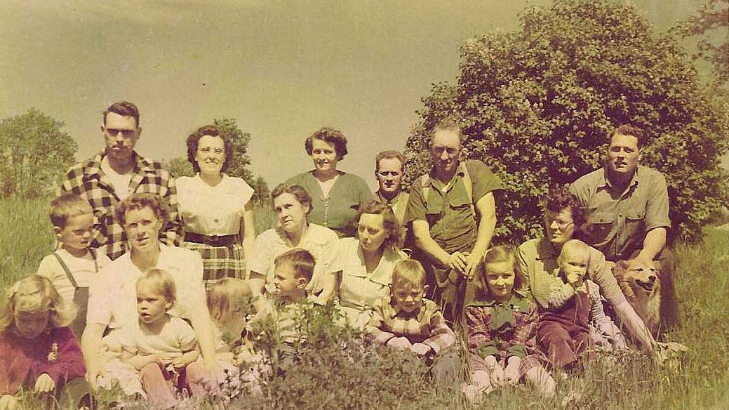 1950s vintage colored family photo with everyone sitting outdoors on the East Coast, including mother and older siblings of Temecula dentist, Dr. Dave Cutts