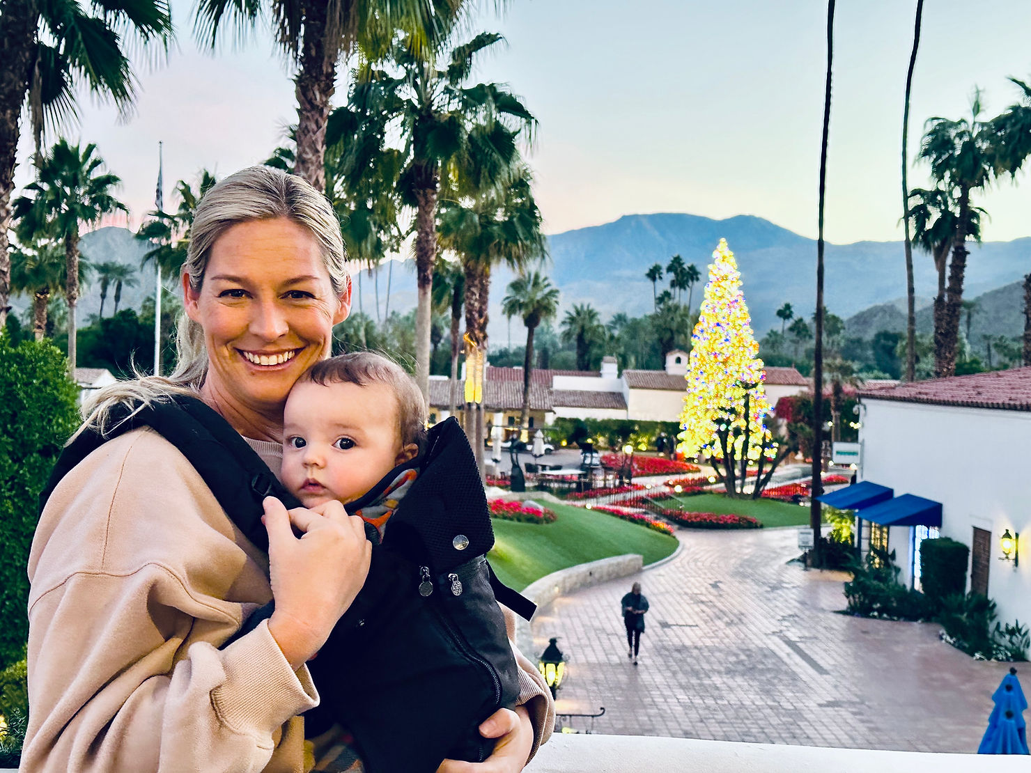 Daughter and infant grandson of Dr. Dave Cutts, expert dentist in Temecula and Riverside County, posing outdoors at a Christmas festival with Southern California mountains in background
