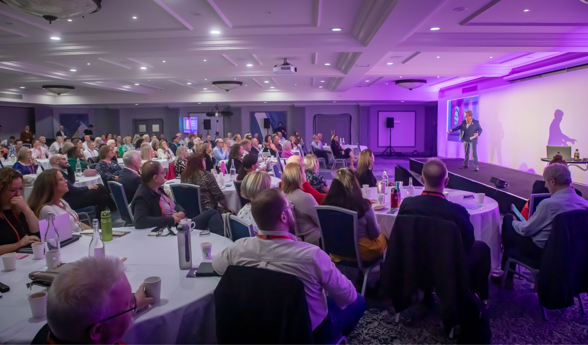 Jackie Handy speaking on stage about inclusion to a packed conference audience