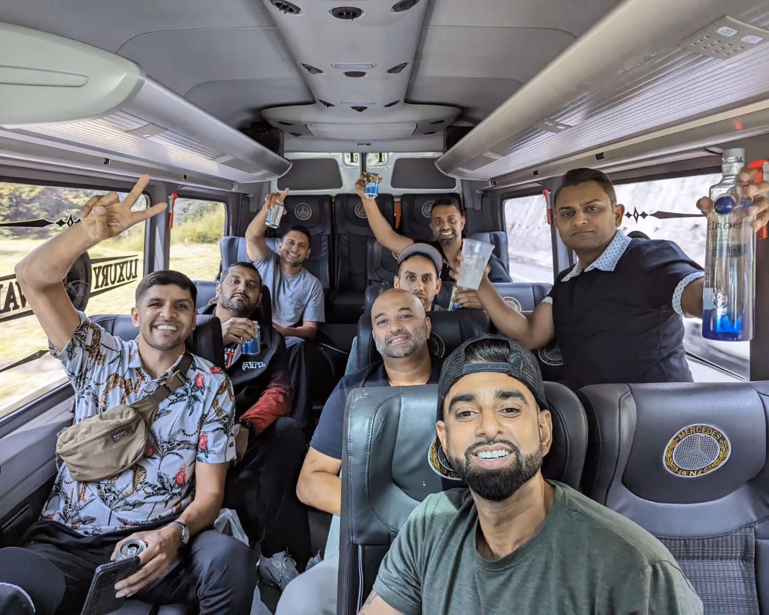 Group of men smiling and holding drinks inside a Mercedes-Benz luxury van.