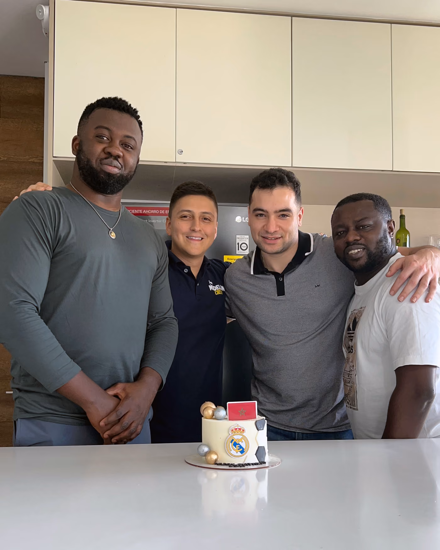 Four men standing behind a cake with a Real Madrid logo and Moroccan flag on a white countertop.