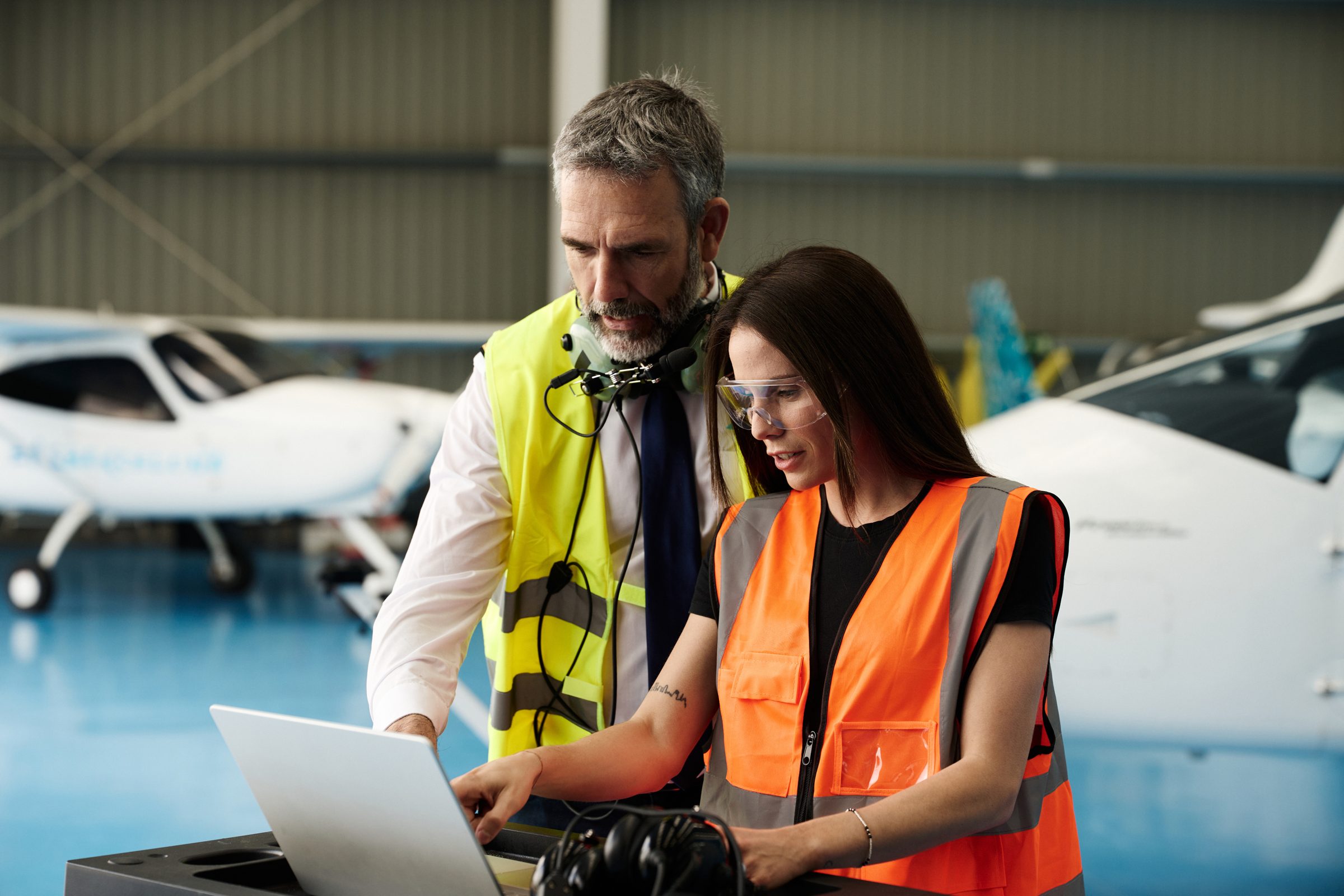 Aviation operations lead and engineer reviewing data on a laptop in an aircraft hangar