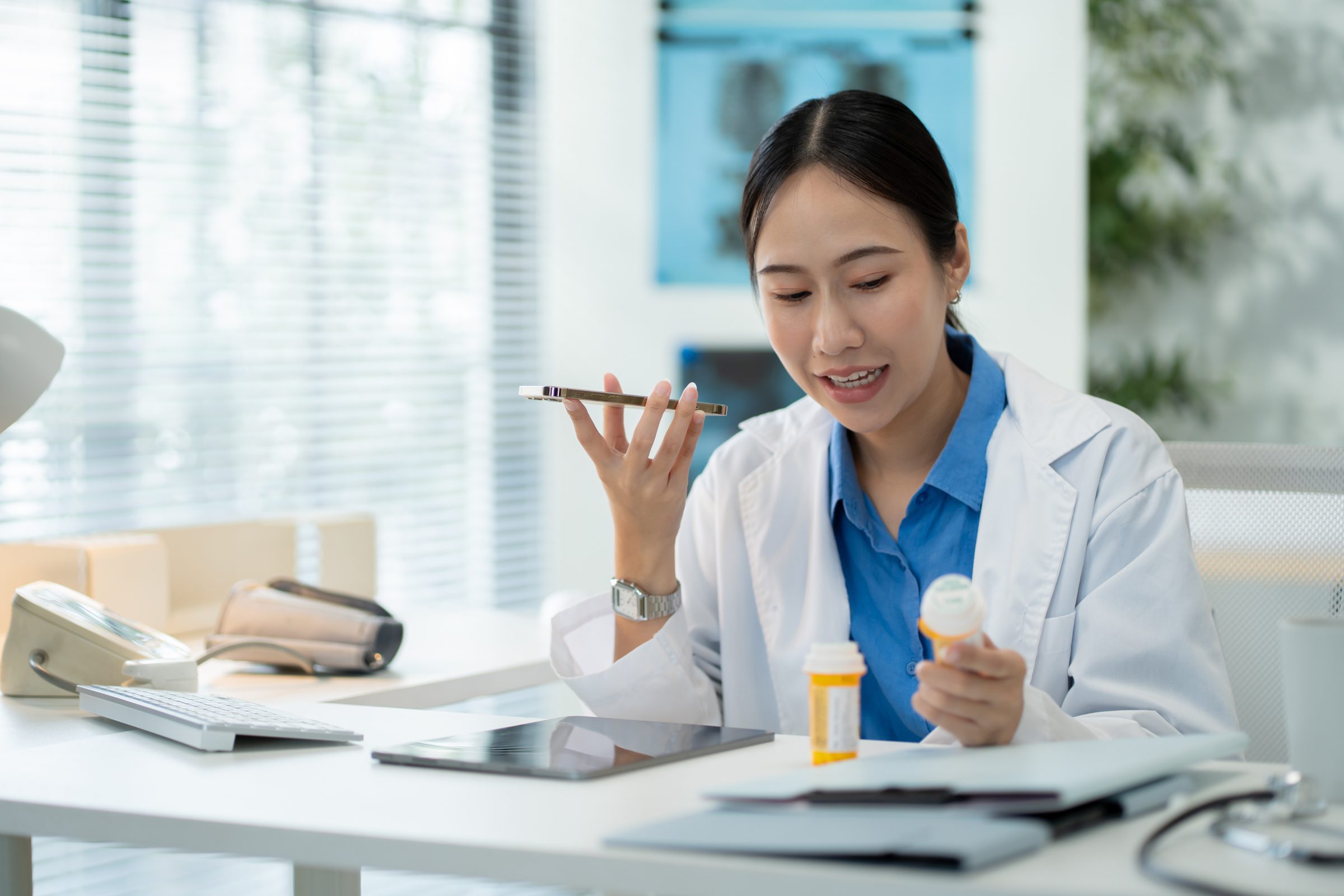 Clinician dictating a note into her phone at her desk