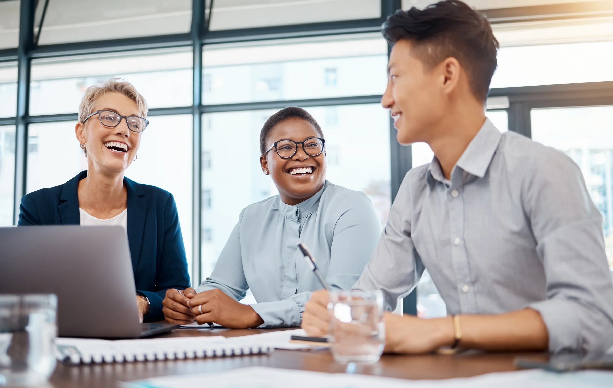 Colleagues laughing together over a laptop