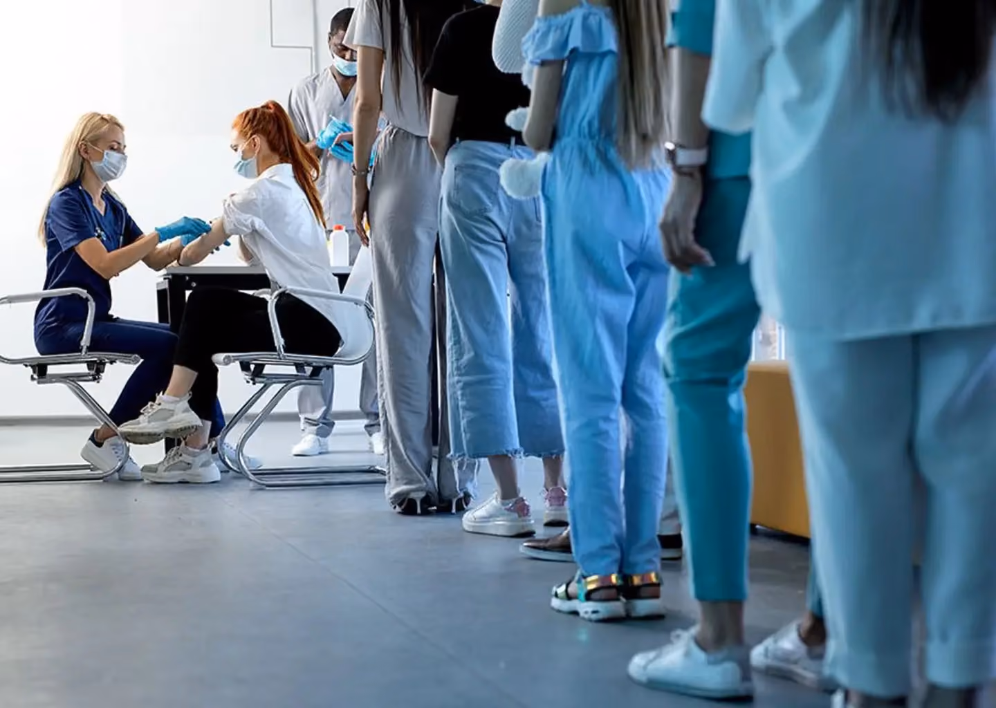 Patients waiting in line at a healthcare facility while medical staff provide care.