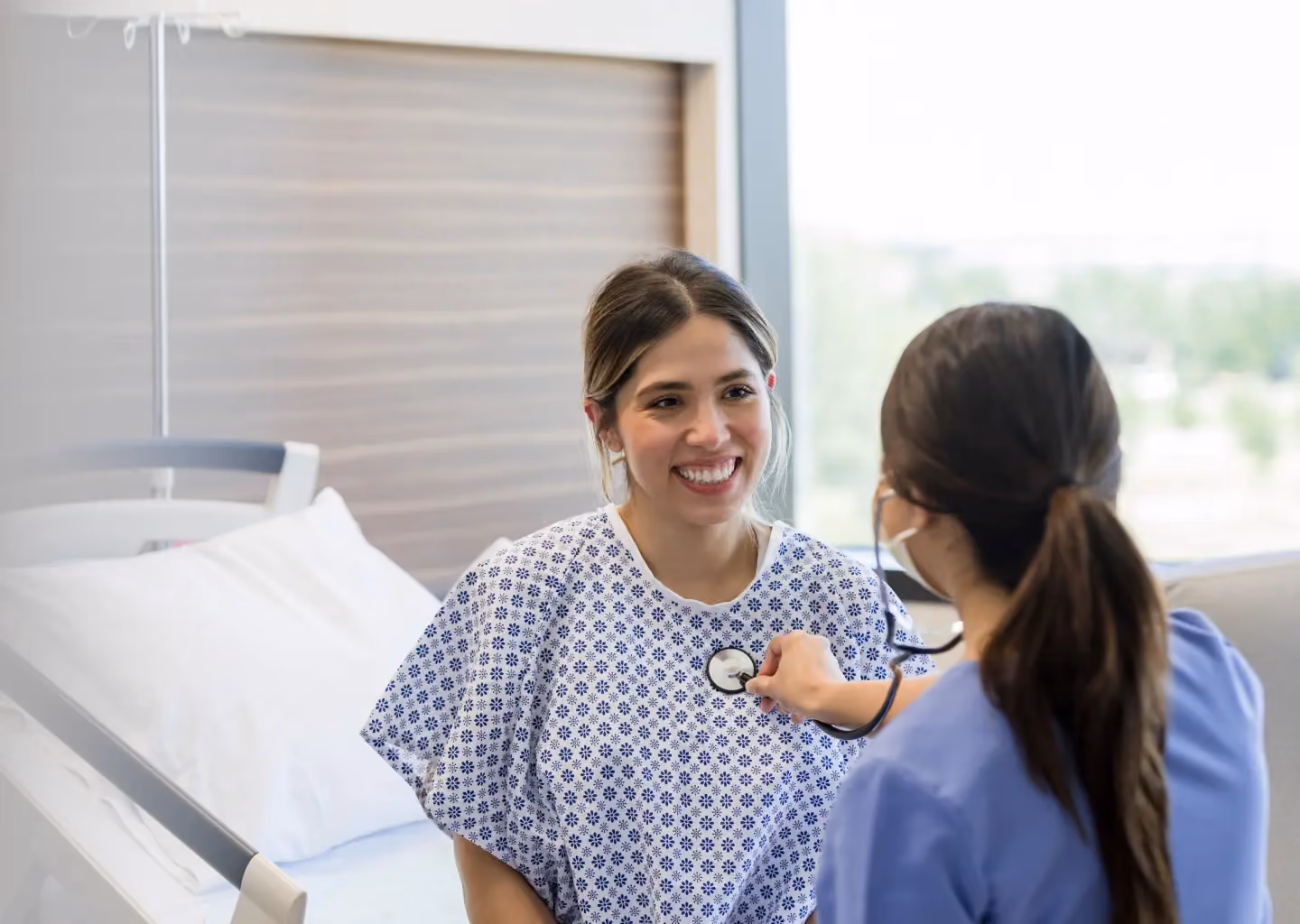 Healthcare provider using a stethoscope to check a patient's vital signs.
