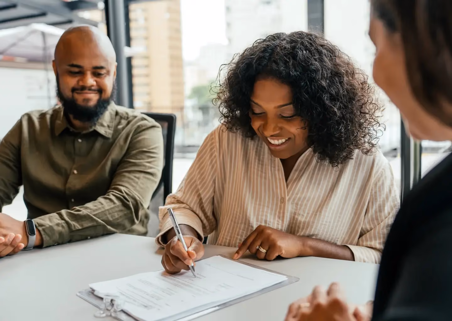 Client signing documents during a meeting with financial or trust advisors.