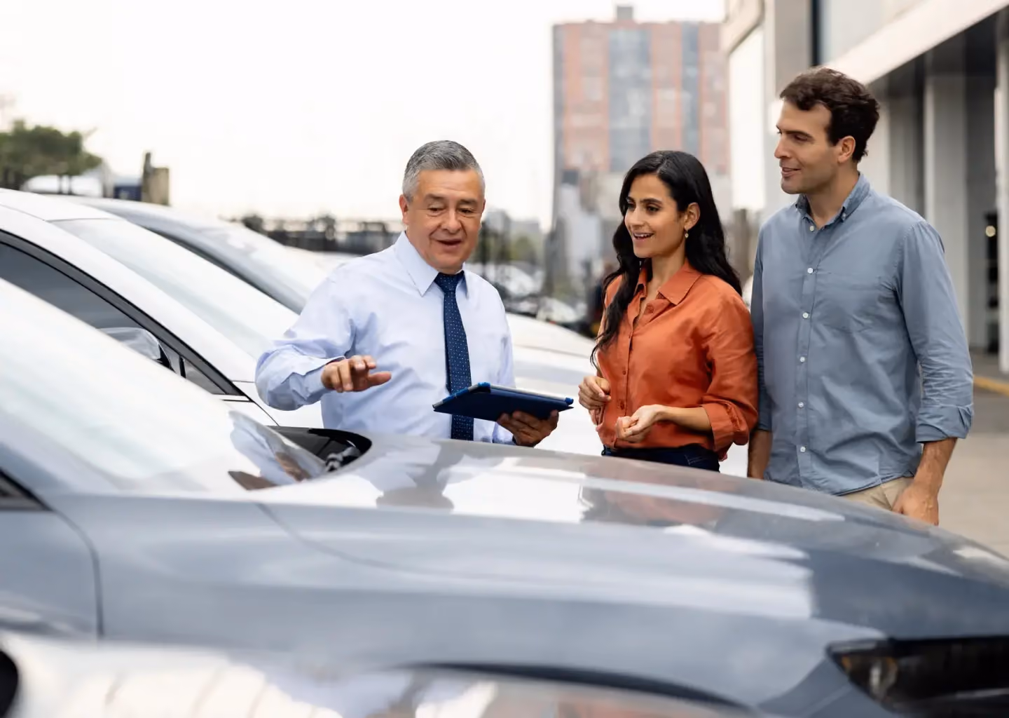 Auto sales representative assisting a couple as they shop for a vehicle at a dealership.