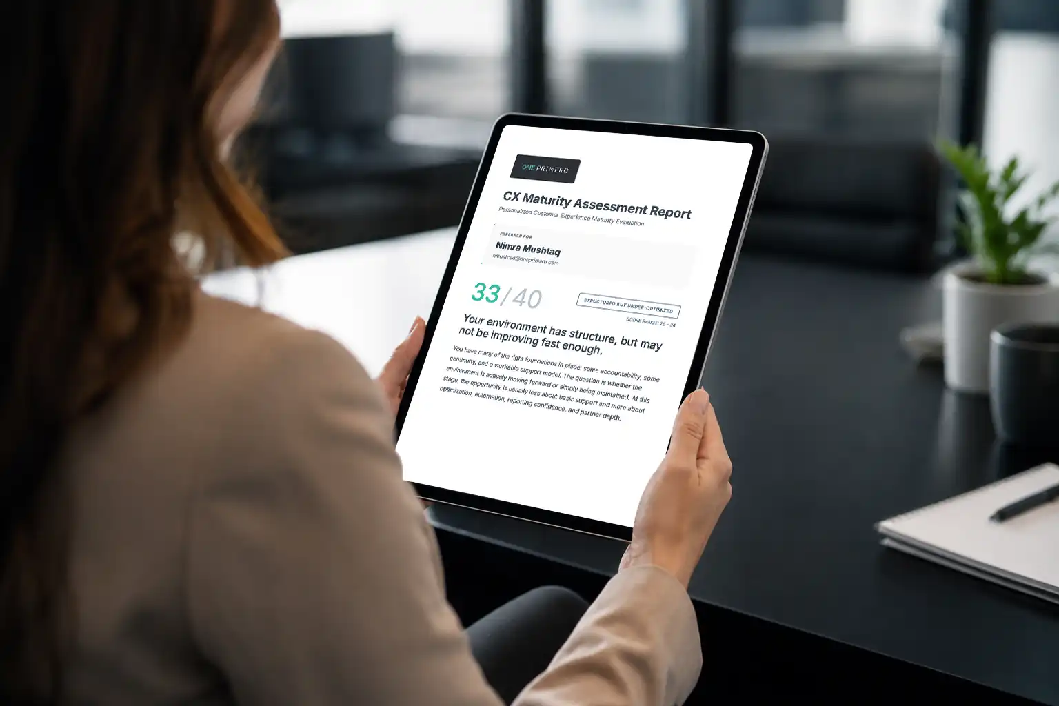 Business professional reviewing a CX maturity assessment report on a tablet in a modern office.