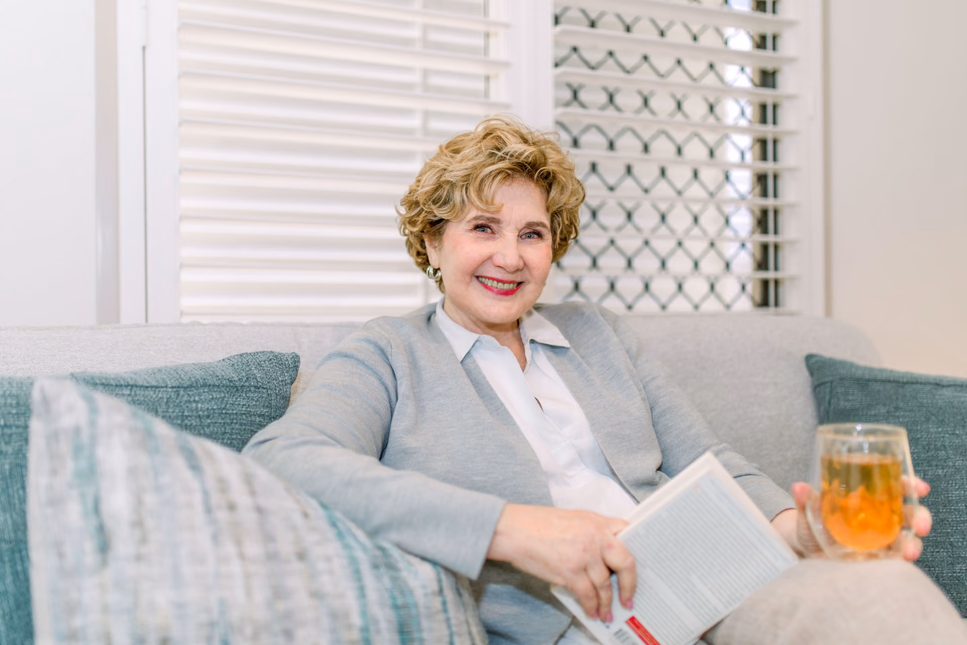 Lynne Gardner relaxing with a book and herbal tea in a calm, welcoming setting
